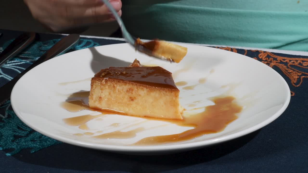 Quesillo venezuelan flan typical dessert with rich caramel, woman hands test with spoon