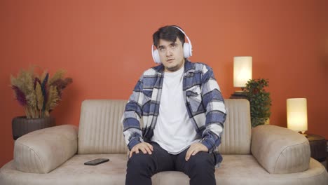 man listening to music with headphones is unhappy and sad.