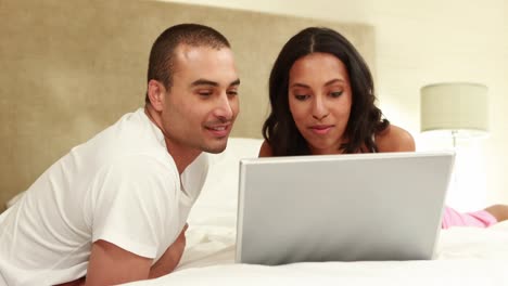 pareja relajada usando una computadora portátil en la cama