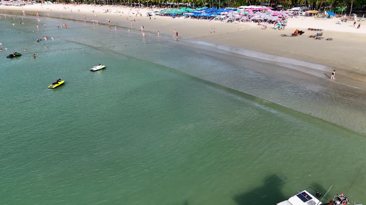 Imágenes de dron capturan la vibrante vida playera en Phuket, Tailandia, mostrando barcos, nadadores y sombrillas coloridas bajo cielos soleados