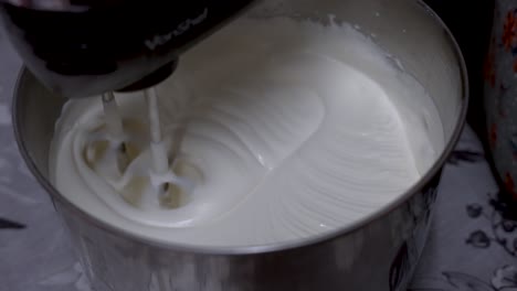 cream being whisked in metal tin by machine on kitchen table