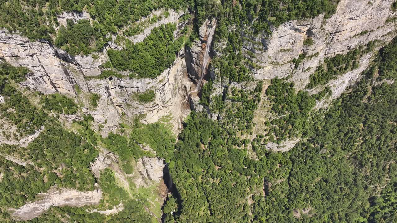 Aerial view of Seerenbach Falls flowing through a narrow gorge surrounded by steep cliffs and dense forest in Switzerland