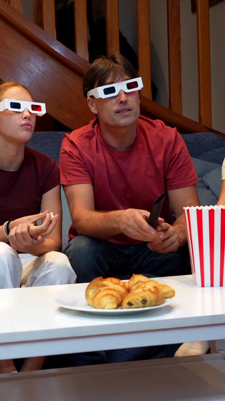Famiglia che guarda un film 3D a casa con popcorn