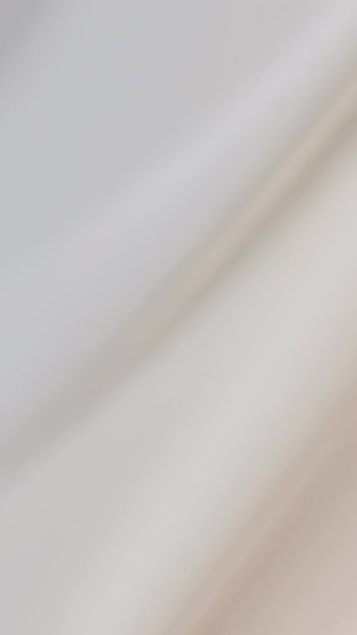 Vertical video: Shifting pale cloth showing diagonal fold in closeup after slight motion, shadowing