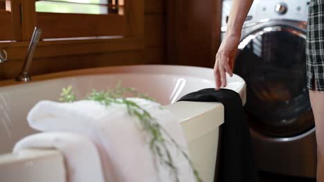 woman placing clothing on the edge of a bathtub