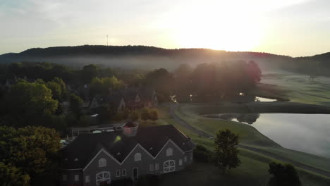Sunrise-aerial-of-house-on-gold-course-greenway-with-lake-in-the-shot