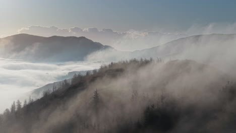 sunrise over misty mountains with soft clouds rolling through the trees in ireland at dawn