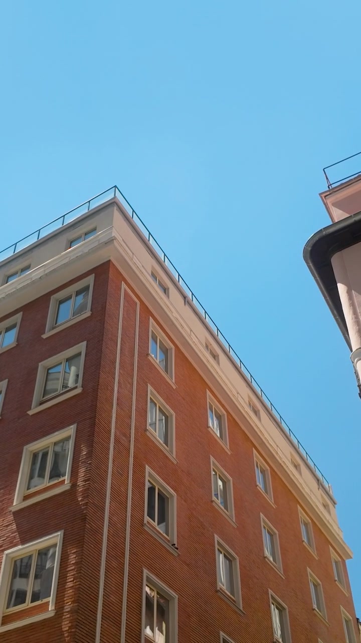 Una ripresa verticale dal basso di classici edifici residenziali a Madrid, Spagna, che mostra l'architettura urbana contro un cielo azzurro limpido. Utile per contenuti di viaggio e immobiliari