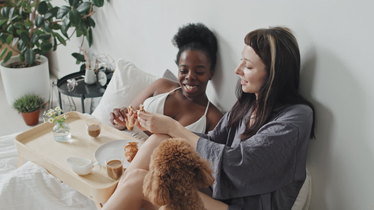 Happy Lesbian Couple and Their Dog Enjoying Breakfast in Bed