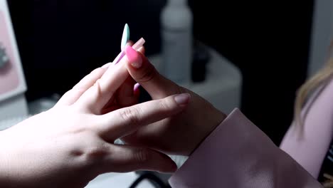 close up of nail stylist adjusting client’s hand during manicure