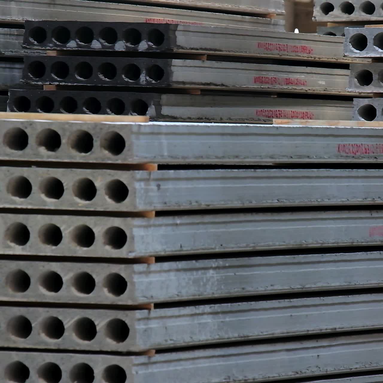 Tumpukan besar pelat beton berarmor untuk konstruksi dengan lubang di dalamnya. Penyimpanan bahan bangunan di pabrik modern
