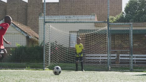 african american soccer kid in red scoring in a sunny day