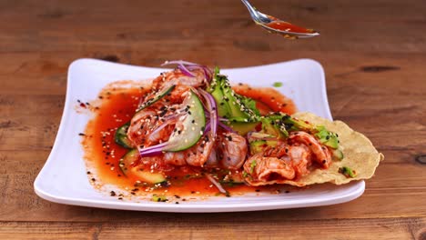 primer plano de un plato de aguachile con tostada de maíz bañada en salsa