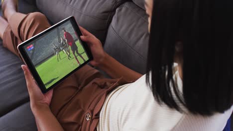 Zusammensetzung-Einer-Frau-Auf-Der-Couch-Zu-Hause,-Die-Sich-Ein-Rugbyspiel-Auf-Einem-Tablet-Ansieht