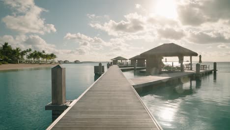 over water cabanas on tropical island on sunny summer day, tranquil blue water on remote destination resort in 4k