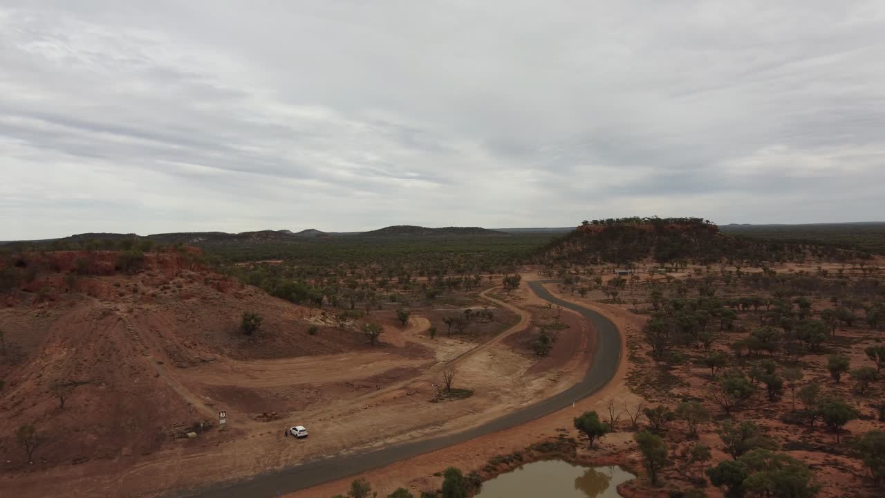 avión no tripulado volando sobre el bosque y un estanque hacia una colina en el interior de australia