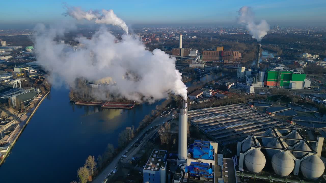 Ciminiere di una centrale elettrica industriale che rilasciano grandi pennacchi di fumo inquinante nell'atmosfera, contribuendo al danno ambientale. Ottima vista aerea dall'alto con drone