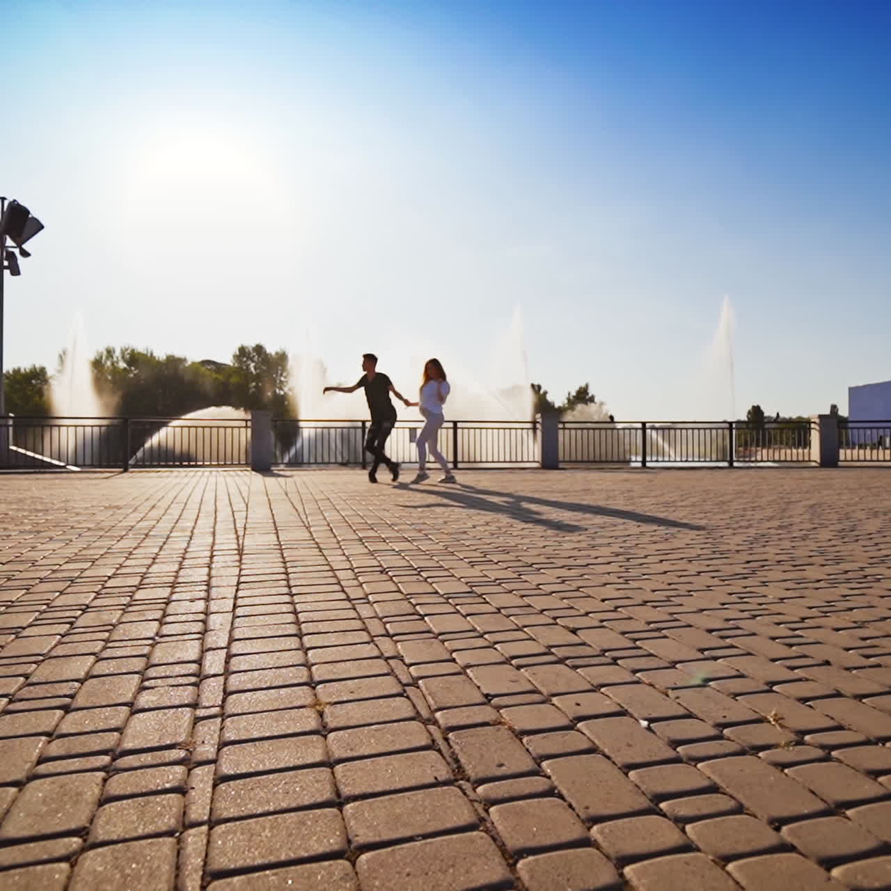 Modern dance of young couple. Beautiful couple on the pavement performing vitality dance. Energetic dance against the fountain.