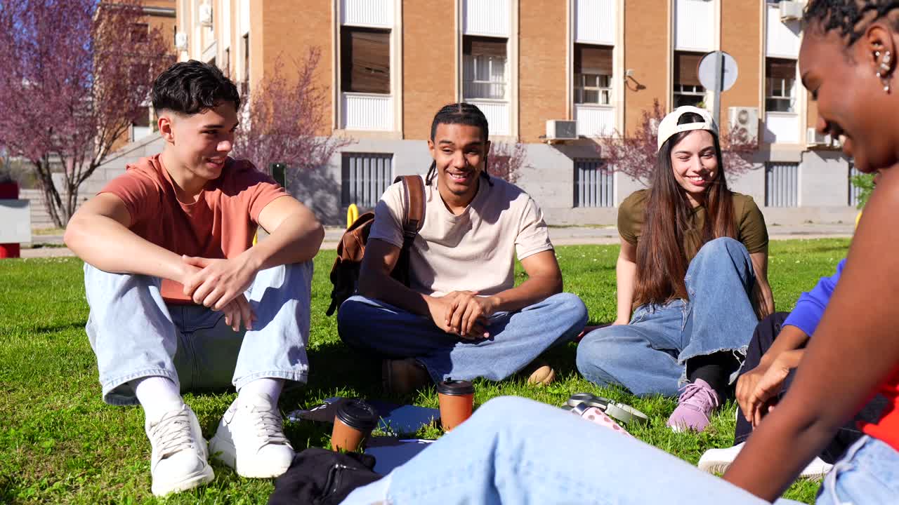 Gruppo di giovani studenti multietnici che socializzano sull'erba del campus