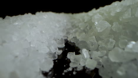 macro dolly slide camera inside crystal coarse sea salt on black mirror surface