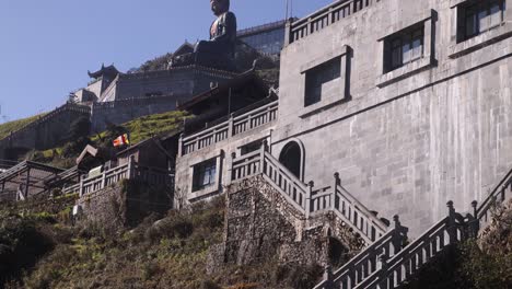 Giant-buddha-statue-and-vietnamese-flag-on-top-of-Fansipan,-the-highest-mountain-in-Indochina-located-in-Sapa,-Vietnam