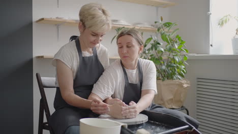 caucasian girl teaches an elderly puppy to work on a potter's wheel. assistance in the rehabilitation and adaptation of pensioners. time-lapse filming of an elderly woman's potter's wheel