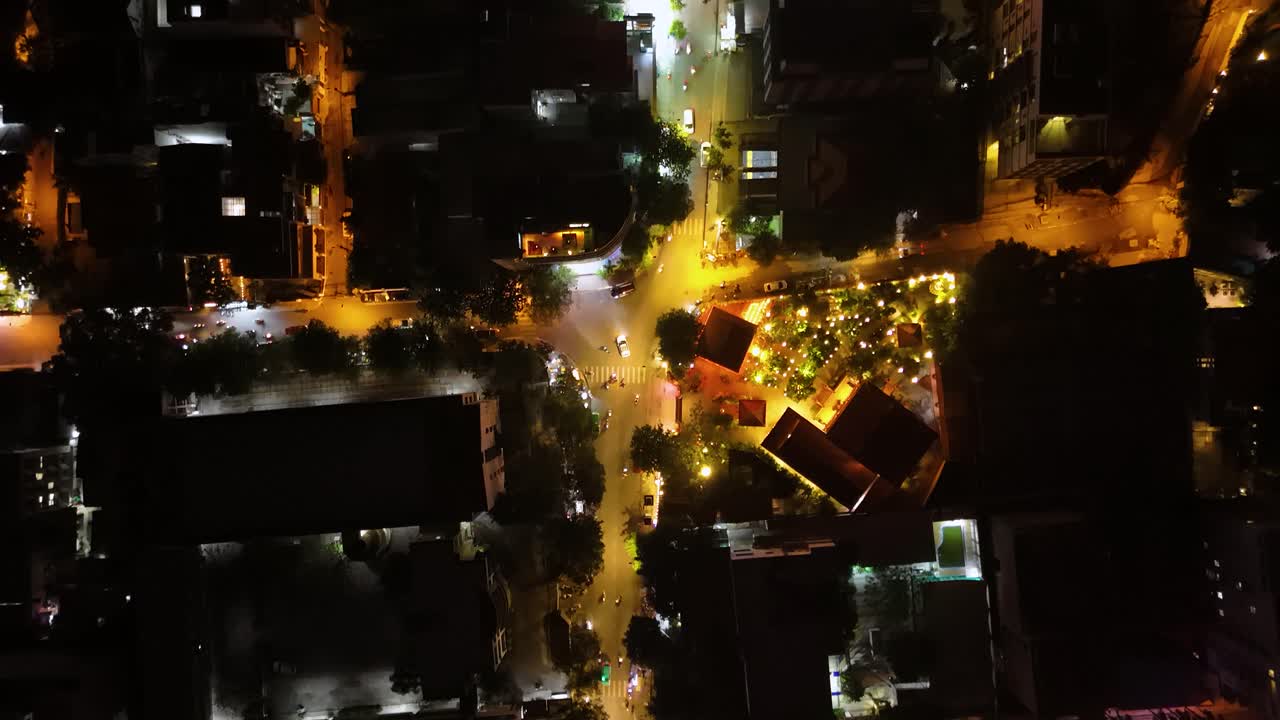 Top-down drone shot of residential areas in Saigon, Ho Chi Minh City, Vietnam. Bright city lights, illuminated streets, tall buildings, and a busy urban atmosphere captured from above.