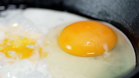 eggs are fried in a frying pan with bubbles of oil.