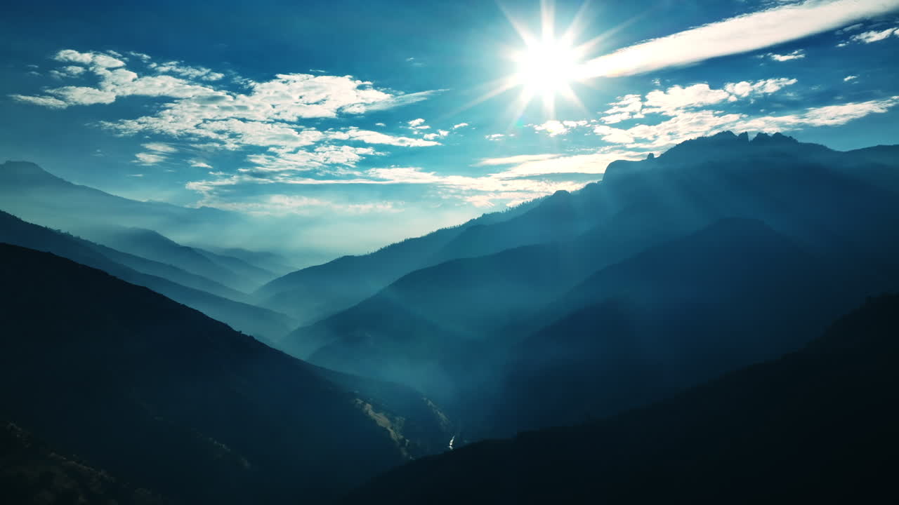Bright sun shining above the mountains of California. Silhouettes of huge rocks in a blue haze.