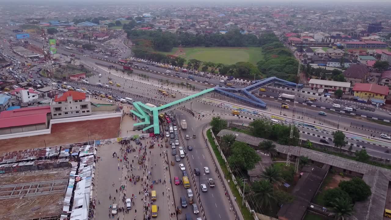 Vista aérea de uma rodovia em Lagos, Nigéria, com uma passarela e carros e caminhões movimentando-se ativamente em meio a um engarrafamento