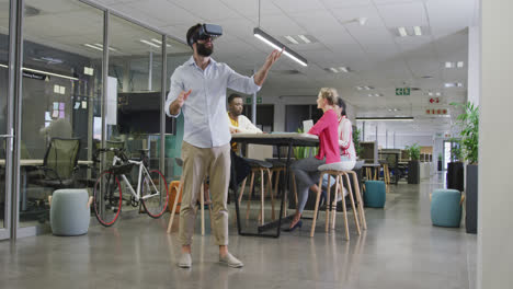 happy biracial businessman using vr headset over colleagues in office