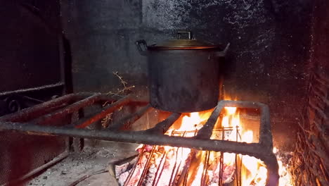comida cocinada en olla negra hecha al fuego, hoguera y paredes negras de fuego