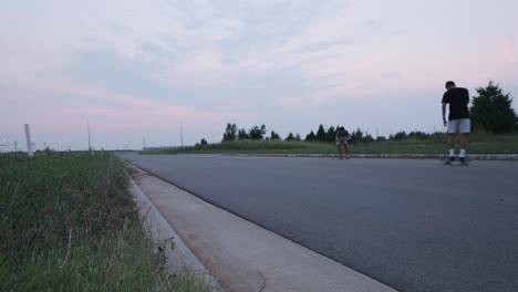 young male adult filming his skateboarder friend performing a kickflip on an empty road