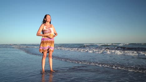 middle-aged woman standing on the beach and doing breathing exercise - wide shot