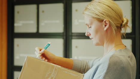 eine frau schreibt eine adresse auf den paketkasten im postamt