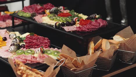 charcuterie board with different fruits and baskets of breadsticks arranged at banquet