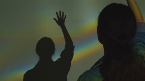 silhouette of woman visiting immersive art exhibition with projection of shapes and patterns on wall 2