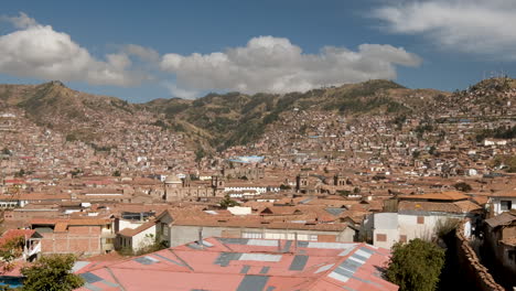 a stunning panoramic pan shot captures the expansive urban landscape of cusco, peru, highlighting its colonial rooftops nestled against the backdrop of the majestic andes mountains