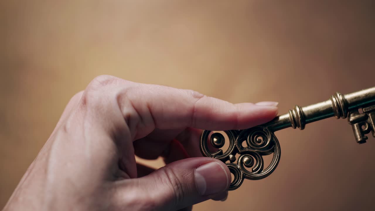 Close-up shot of a hand holding an ornate key, shot from a side angle