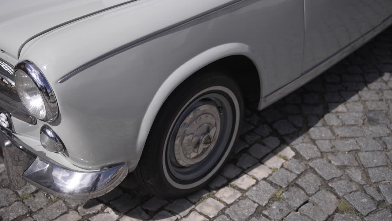 Close up of classic white car parked on cobblestone street in daylight