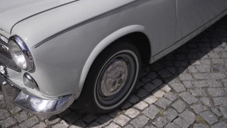 close up of classic white car parked on cobblestone street in daylight