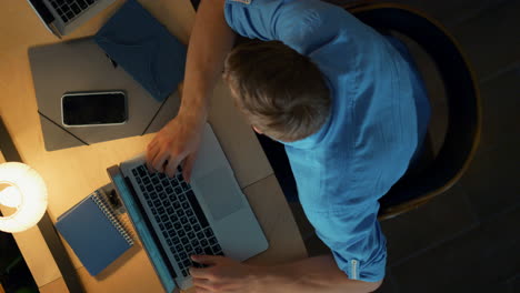 Busy-man-talking-colleagues-in-dark-office.-Overworked-guy-typing-computer