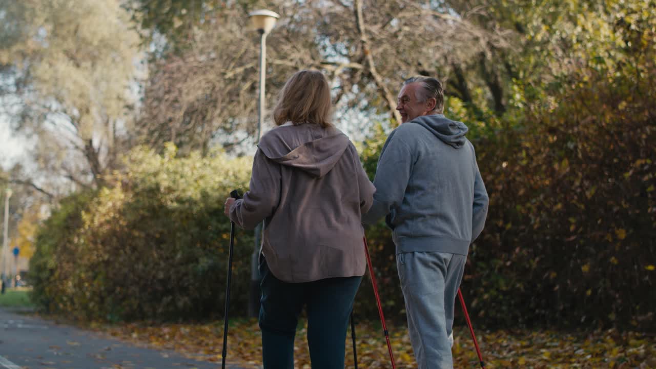 vista trasera de una pareja de ancianos caucásicos nórdicos caminando en el parque