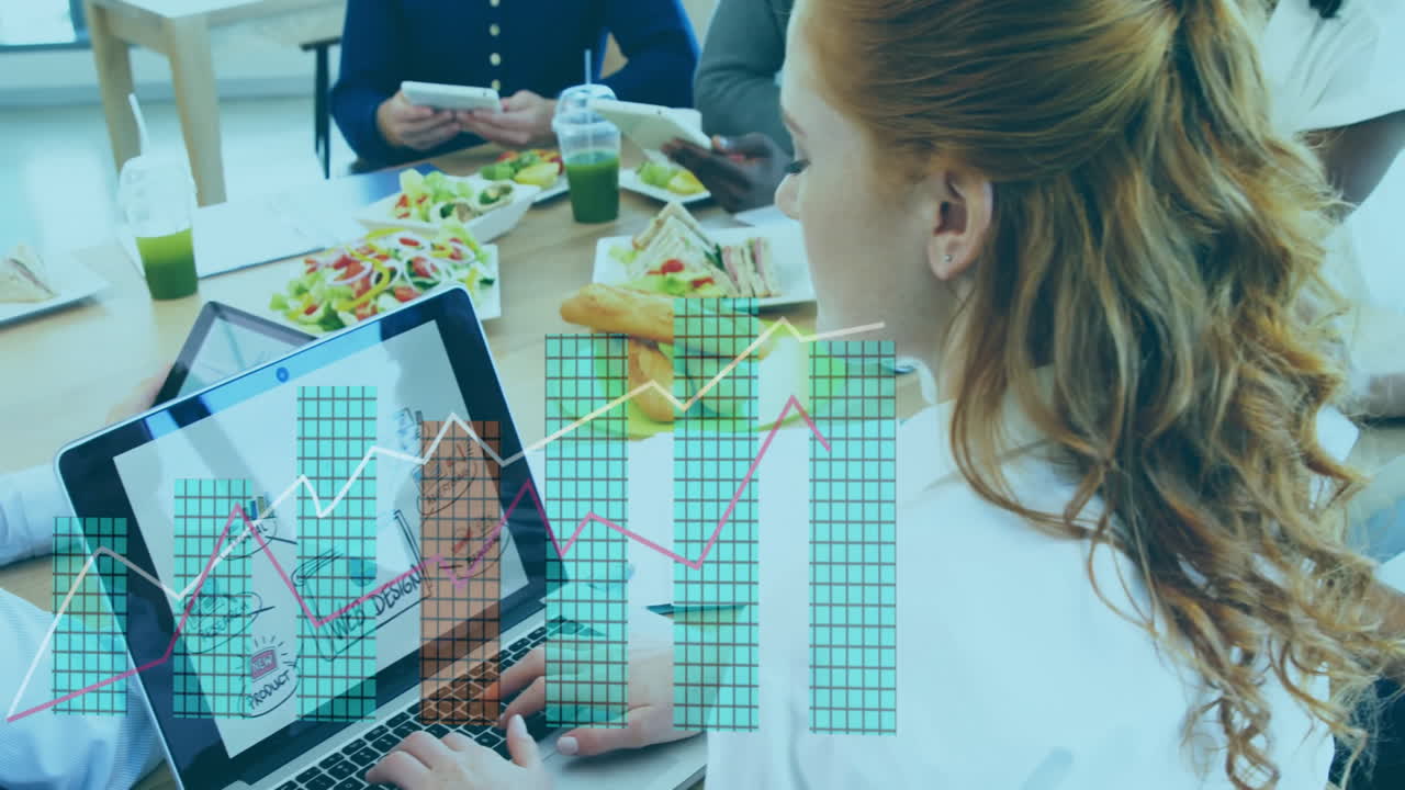 Businesswoman working on laptop with graph animation over colleagues having lunch