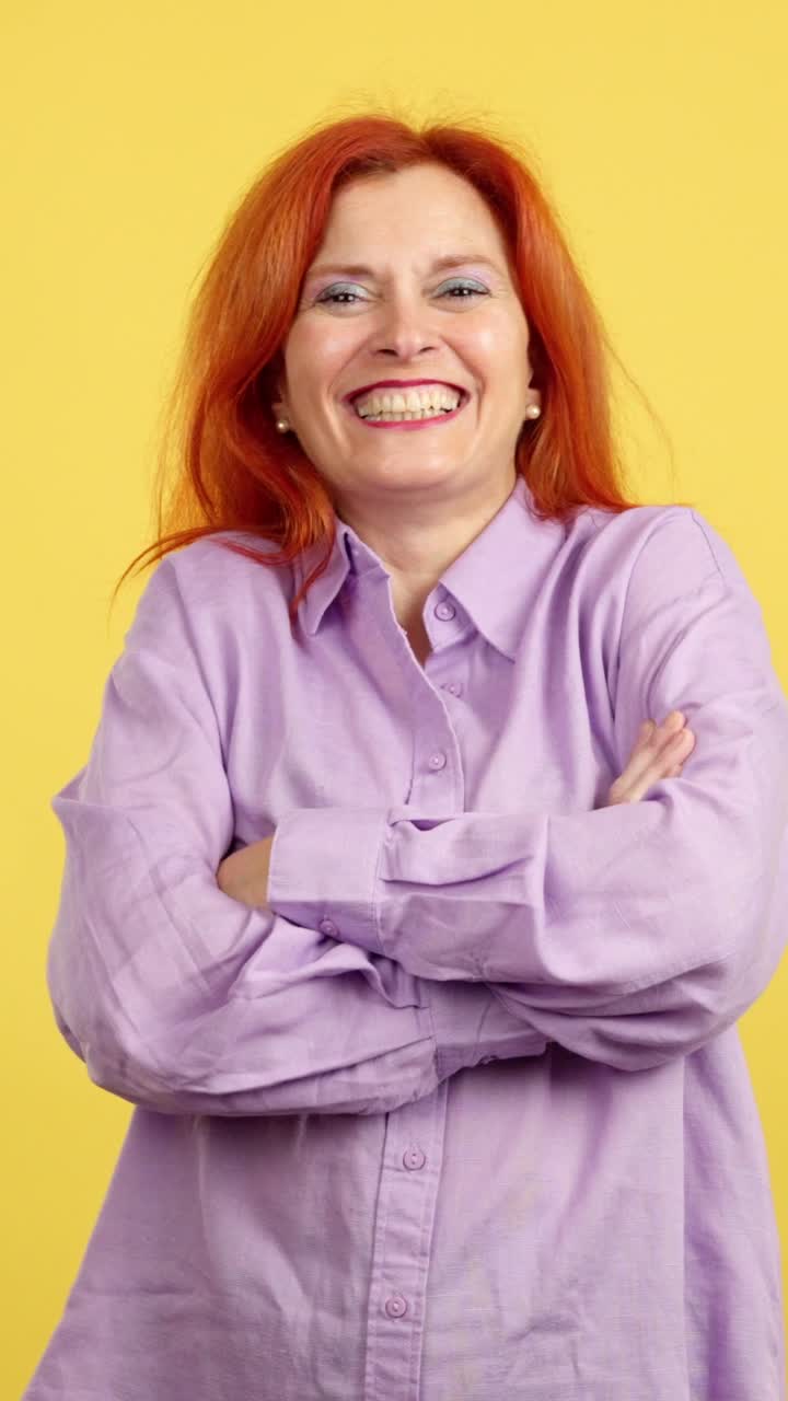 Woman with red hair smiling and laughing against a yellow background