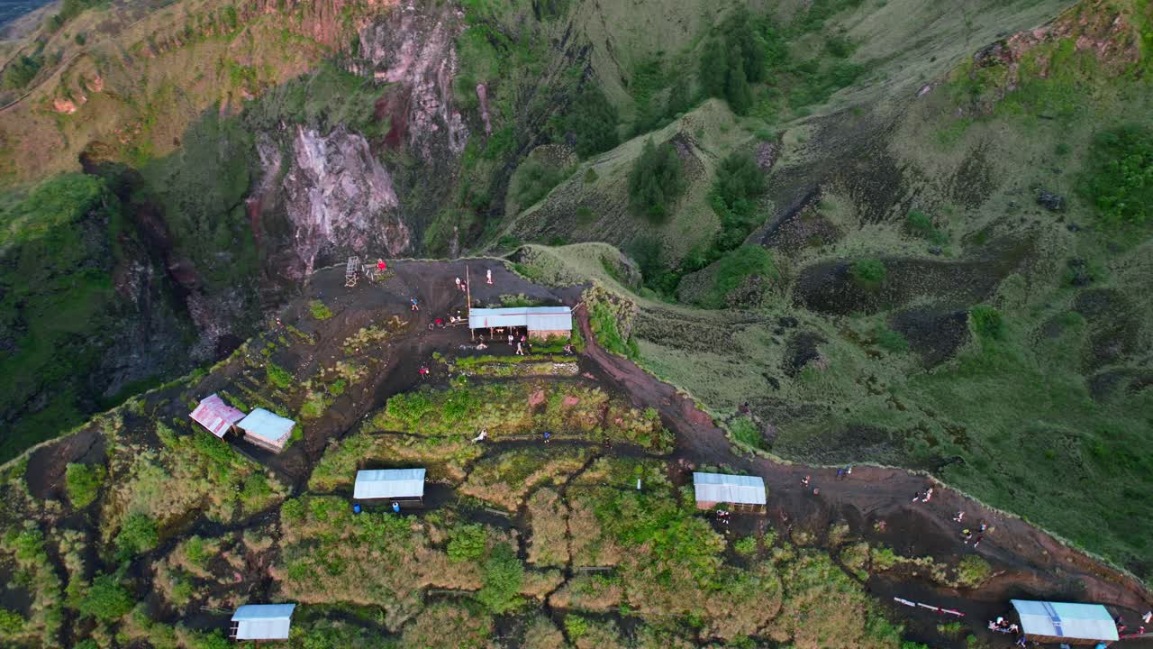 vista aérea de turistas en el acantilado del cráter del volcán monte batur durante el amanecer en bali, indonesia