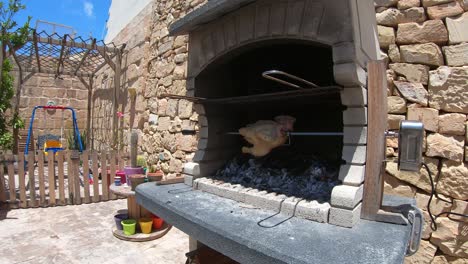 pollo rostizado girando en una barbacoa de ladrillos de fuego de madera y carbón en avance rápido