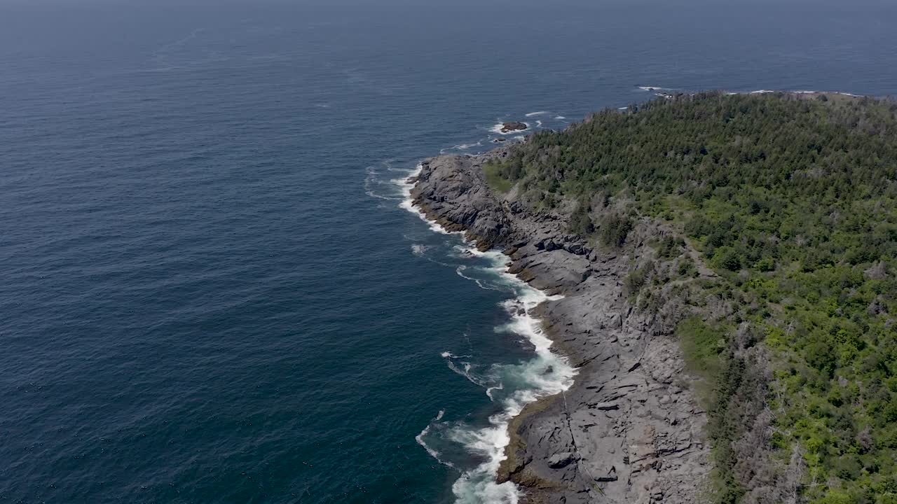 Ripresa con drone che si alza dalla costa nel Maine con le onde che si infrangono sugli scogli