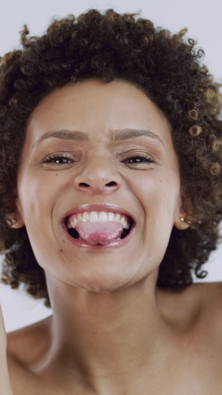 Primo piano di una giovane donna felice con i capelli ricci che sorride in modo giocoso