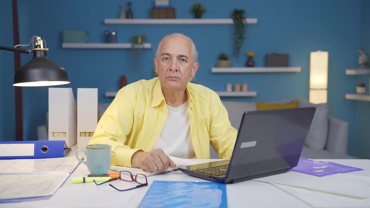Home office worker old man looking dull at camera.